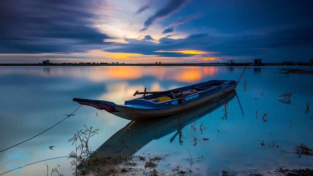 Chiếc thuyền giữa lòng hồ dầu tiếng khi mặt trời lặn